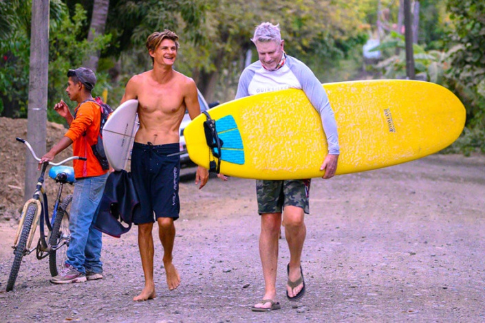 Collin Walker walks his surf lesson down road in Nosara